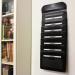 The image shows a compact, black Polypropylene hanging organizer with seven pockets. The interior features a cathedral design, creating a unique and stylish look. The product is designed to expand, allowing for more storage space for A4-sized documents. Ideal for keeping files organized and easily accessible, this portable wallfile is a great addition to any workspace or office.